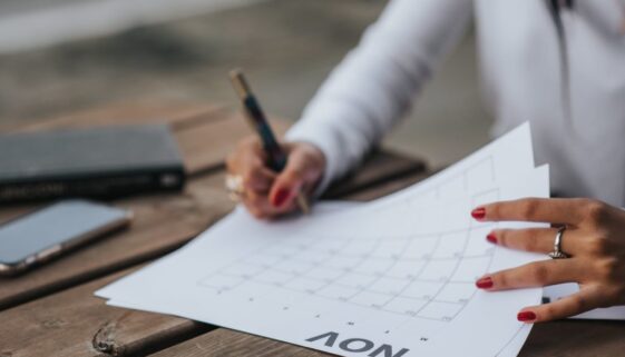crop woman filling calendar for month